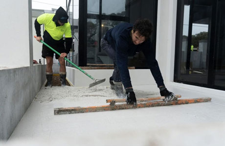 Concreters smoothing out the concrete before bringing the aggregate to the surface