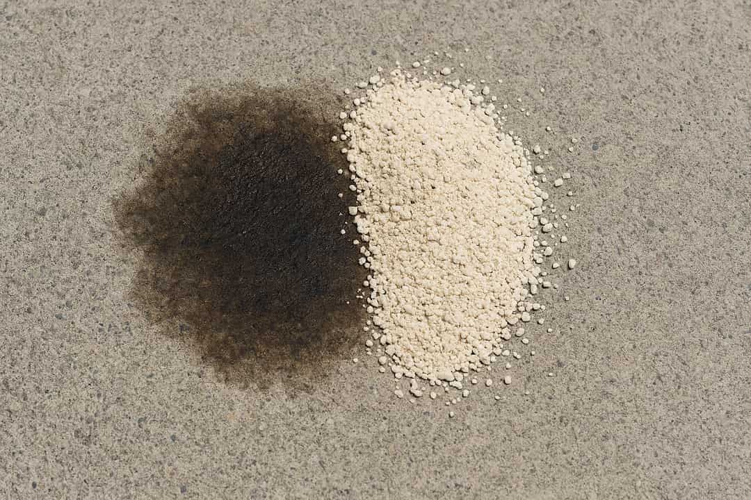 Sawdust applied to a fresh oil stain on a concrete driveway to absorb the spill.